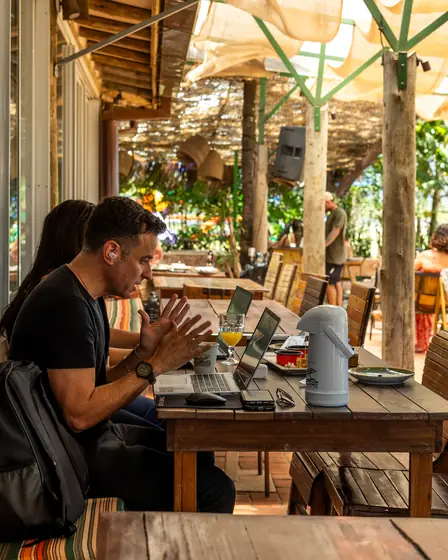 Pessoas trabalhando com notebooks e garrafa de café no deck do Clericot